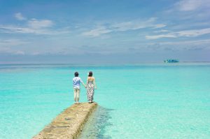 deux personnes sur ponton devant mer turquoise