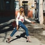 femme qui marche dans la rue avec pull blanc jean et bottines velours