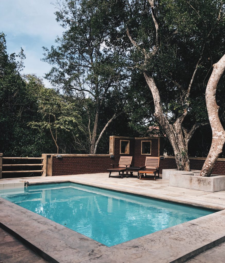 extérieur avec piscine et transats en bois sous des arbres