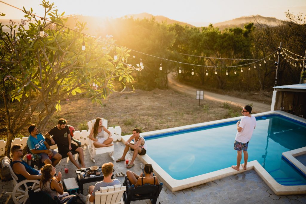 extérieur avec piscine et guirlande lumineuse groupe de personnes assises près de la piscine buvant un verre