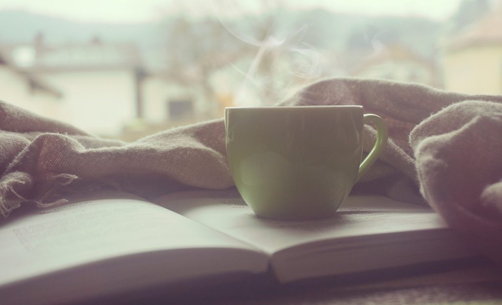 tasse avec boisson chaude fumante posée sur un livre