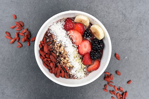 bol avec des fruits coupés des graines de la noix de coco rapée