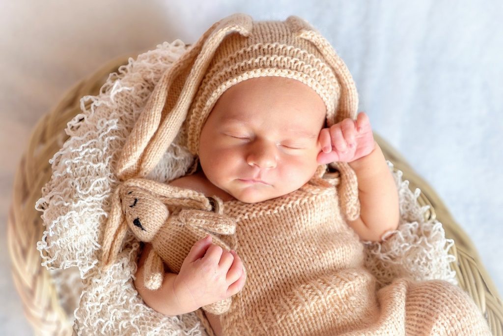 Bébé avec un bonnet et un doudou lapin tricotés